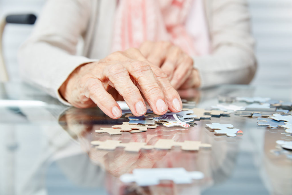 Elderly woman doing a puzzle on a glass table