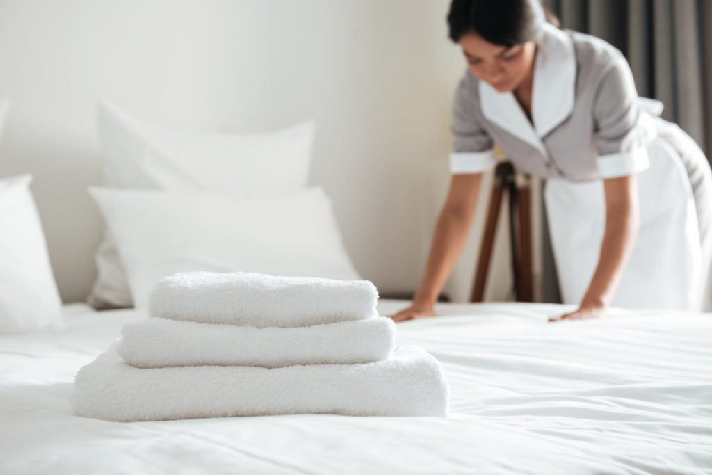 A housekeeper folding a resident's towels on their recently made bed