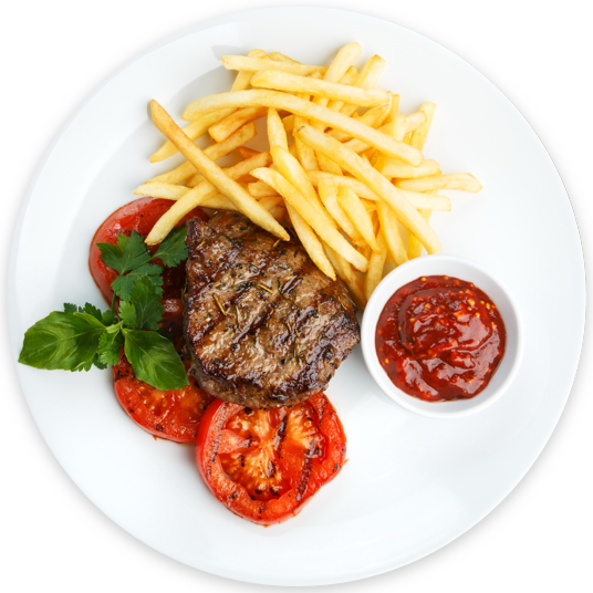 Steak and fries on a white plate with ketchup and tomatoes