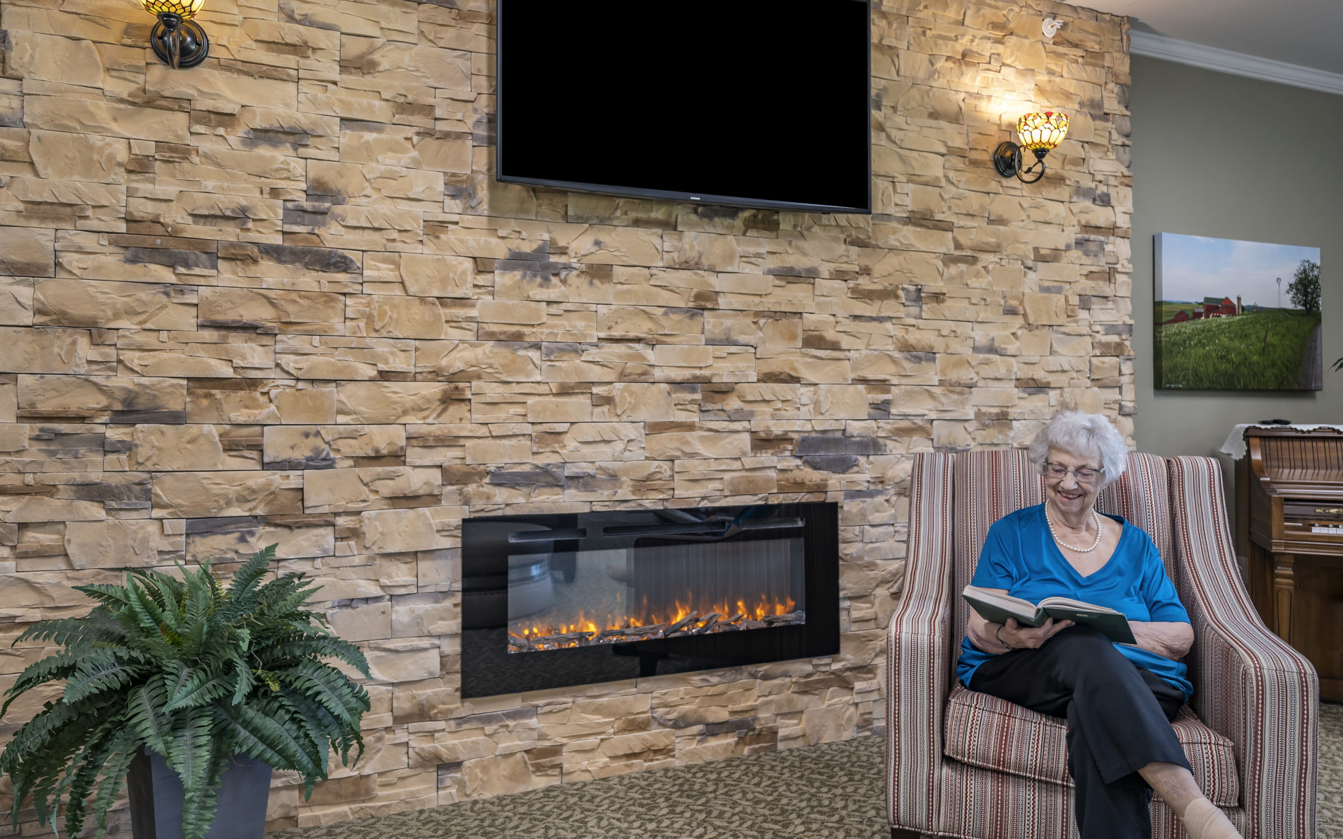 Senior woman reading by fireplace