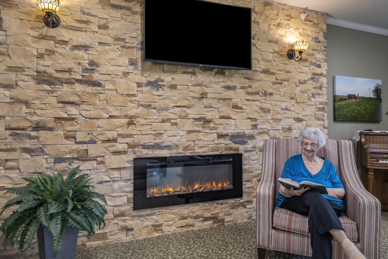 Senior woman reading by fireplace